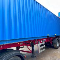 A blue 40ft shipping container on a trailer parked in a yard with other containers in the background.