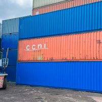A stack of colorful 40ft shipping containers with a forklift positioned nearby for loading or unloading.