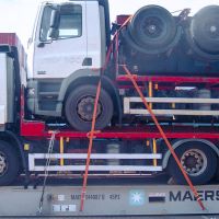 A stacked truck and trailer secured on a shipping container, with visible wheels and cargo ties.