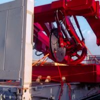 Red industrial machinery on a shipping container, with a Maersk logo and clear sky in the background.