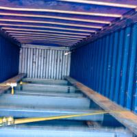 A view inside a blue shipping container, showing straps and metallic structure along the floor.