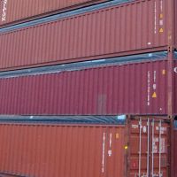 A stack of colorful shipping containers, including red and blue, showing various labels and logos.