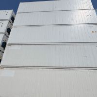 Stacked containers in a storage yard, with a logo for Acorn Containers in the foreground against a clear blue sky.